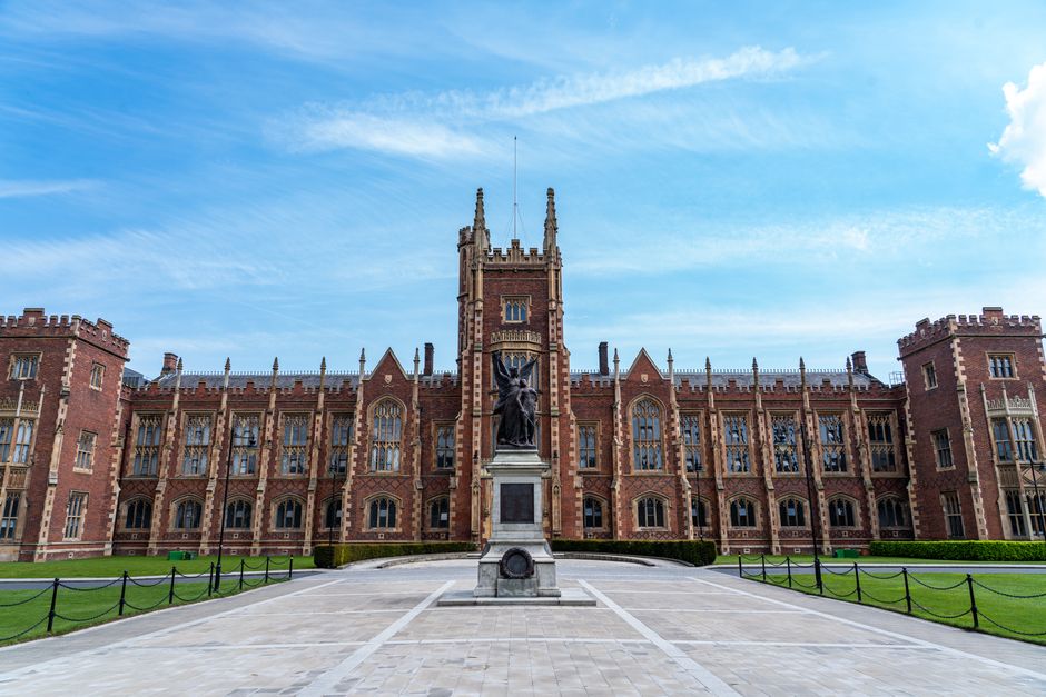 A stunning view of a historic university building in Ireland with a prominent monument in front.