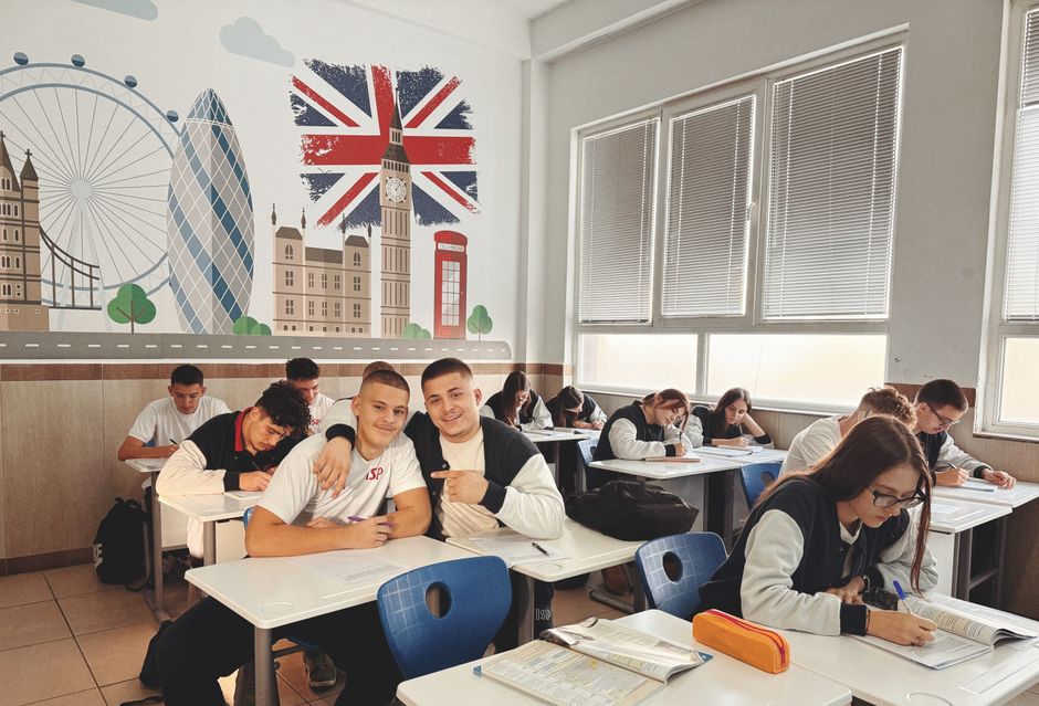 Students studying in a classroom featuring a mural of London landmarks and British flag.