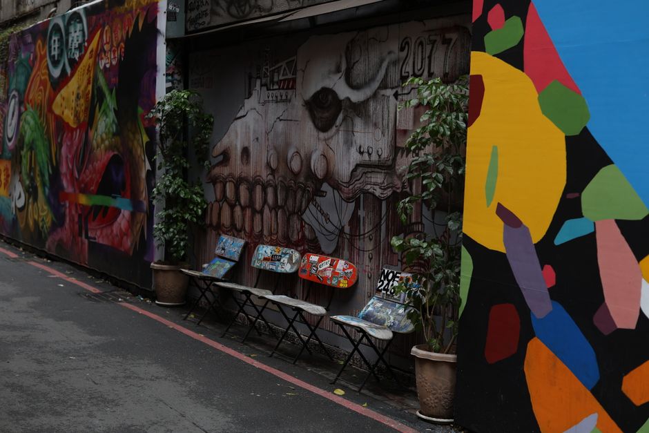 Vibrant graffiti art and skateboards in a Taipei alleyway.