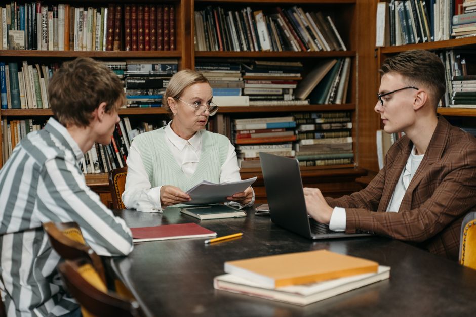 A focused group discussion among adults in a library with bookshelves.