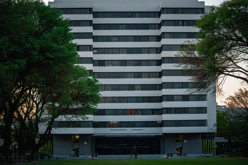 Modern university building exterior in Pretoria surrounded by trees.